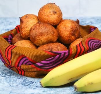 Bowl of Puff Puffs wraped in kente cloth next to two banana